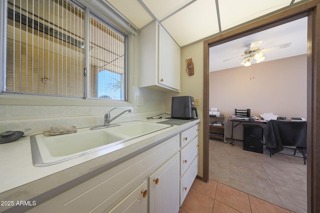 kitchen with light tile patterned floors, light countertops, a sink, and white cabinets