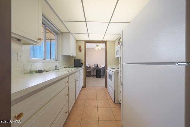 kitchen with light countertops, white cabinetry, a sink, light tile patterned flooring, and white appliances