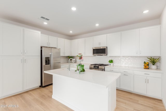 kitchen with light wood-style floors, visible vents, appliances with stainless steel finishes, and light countertops