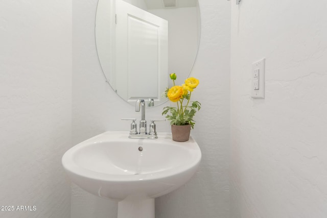 bathroom featuring a textured wall and a sink