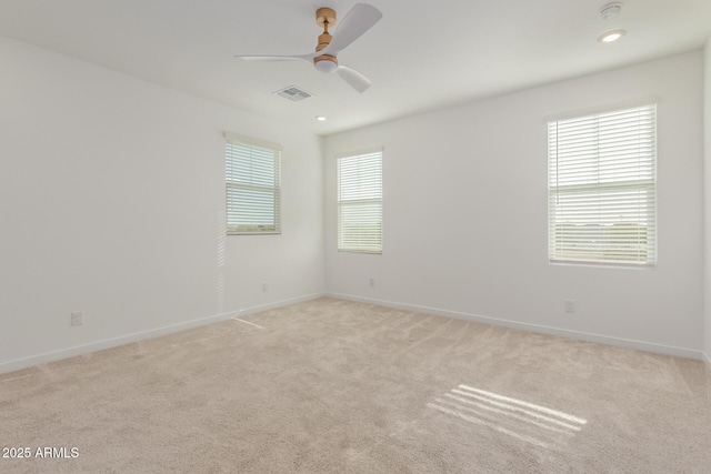 empty room featuring light carpet, ceiling fan, visible vents, and baseboards