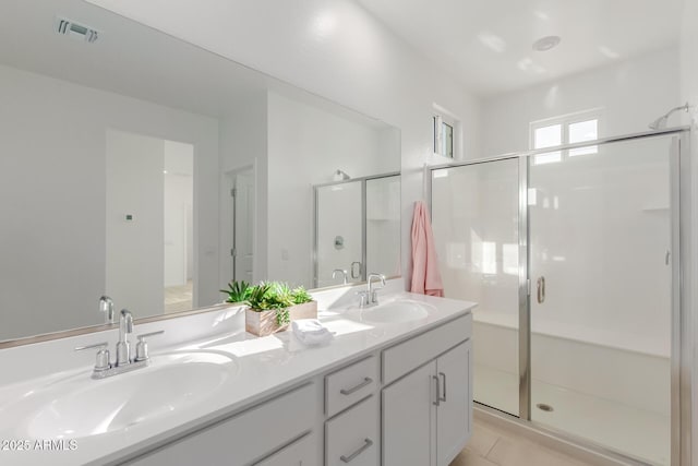 full bathroom with double vanity, a sink, visible vents, and a shower stall