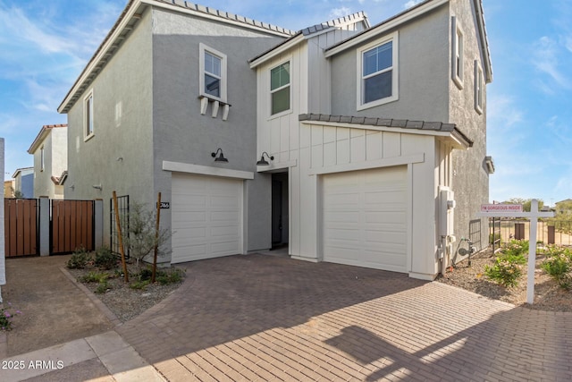 view of front of property featuring decorative driveway, an attached garage, fence, and stucco siding