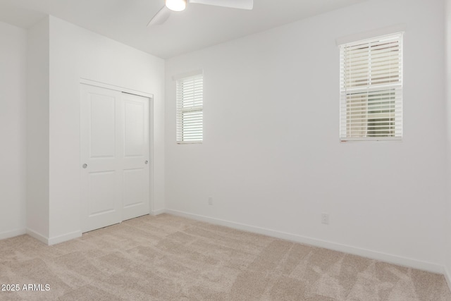 spare room featuring light carpet, ceiling fan, and baseboards