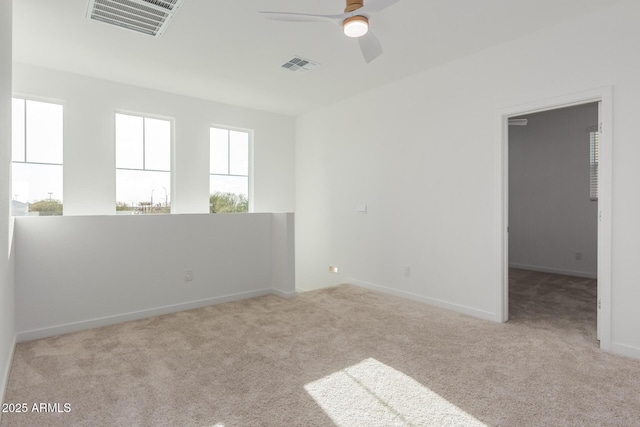 carpeted spare room with visible vents, ceiling fan, and baseboards