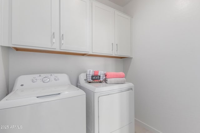 clothes washing area with cabinet space, baseboards, and washer and dryer