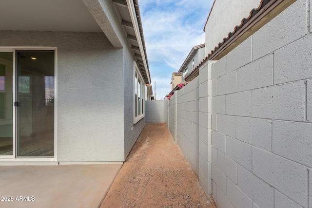 view of side of home with fence and stucco siding