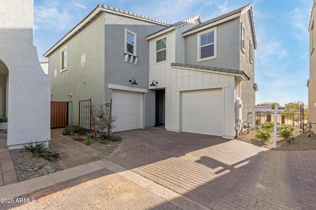 multi unit property with fence, decorative driveway, and stucco siding