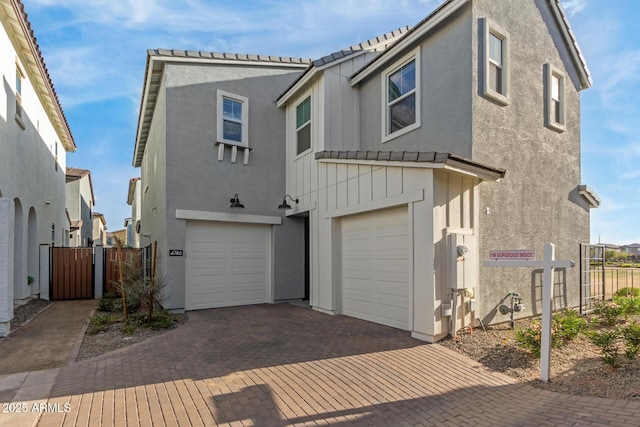 view of front facade with decorative driveway, fence, an attached garage, and stucco siding