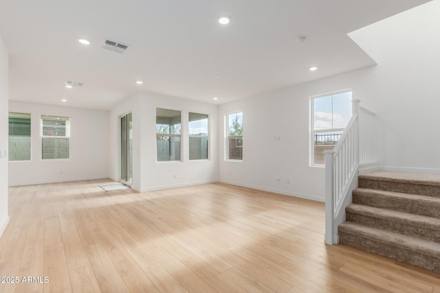 unfurnished living room with stairs, recessed lighting, baseboards, and light wood-style floors