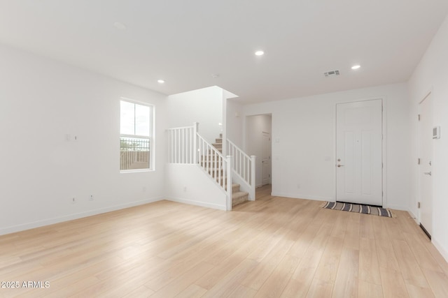 unfurnished room featuring light wood finished floors, recessed lighting, visible vents, stairway, and baseboards