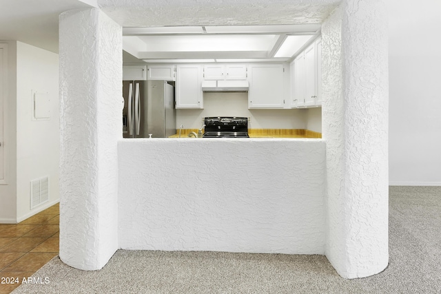 kitchen featuring carpet, stainless steel fridge, white cabinetry, and black range oven