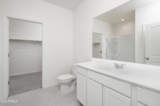 bathroom with tile patterned flooring, vanity, a shower with shower door, and toilet