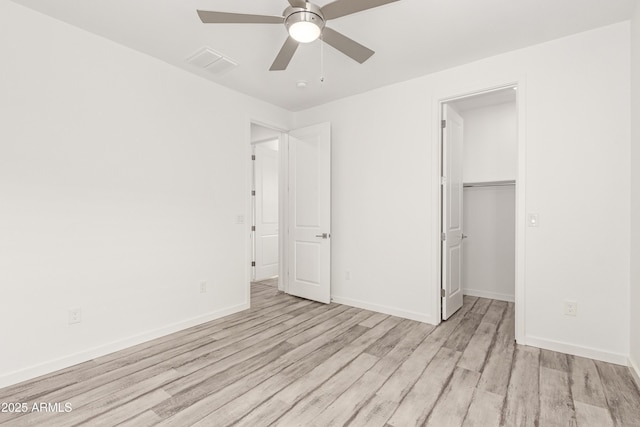 unfurnished bedroom with a closet, ceiling fan, a spacious closet, and light hardwood / wood-style floors