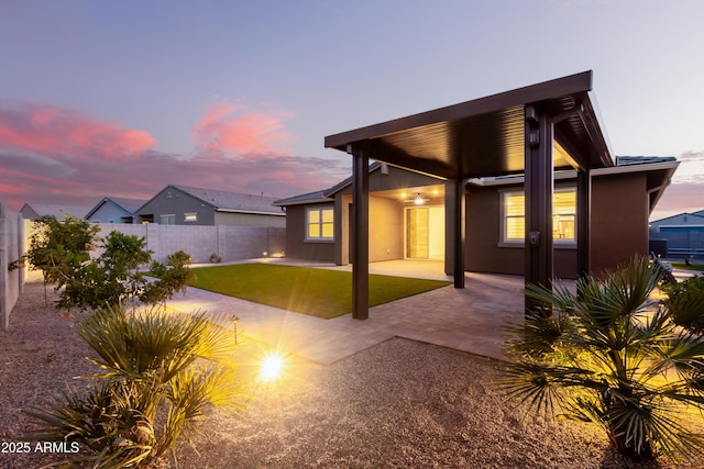 back house at dusk featuring a patio area and a yard