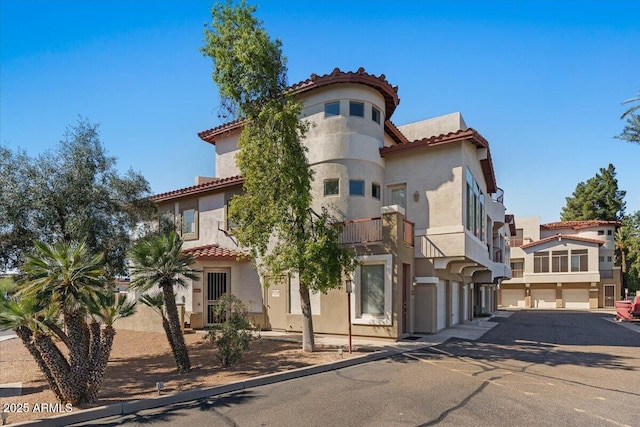 view of front of home featuring stucco siding, a tiled roof, an attached garage, and driveway