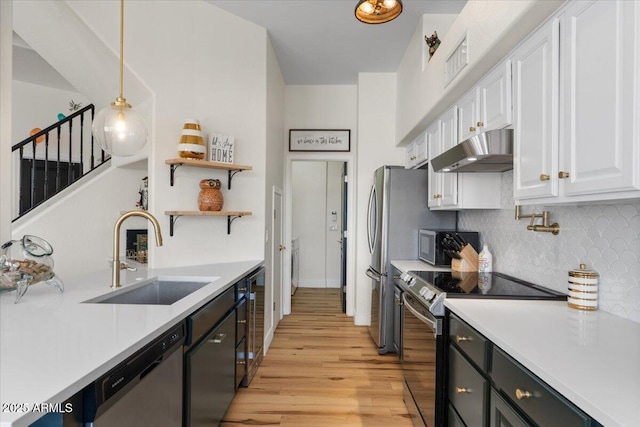 kitchen with under cabinet range hood, light countertops, white cabinets, stainless steel appliances, and a sink