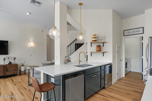 kitchen featuring light wood finished floors, visible vents, wine cooler, stainless steel dishwasher, and a sink