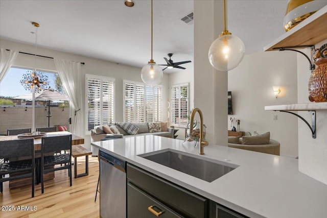 kitchen with a sink, stainless steel dishwasher, open floor plan, and light countertops