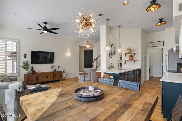 dining area featuring visible vents, ceiling fan with notable chandelier, light wood-style floors, washer / dryer, and stairs