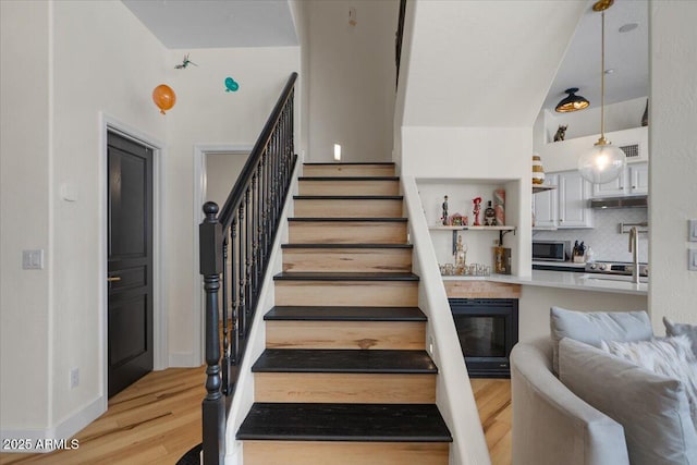 stairs with baseboards, wine cooler, and wood finished floors