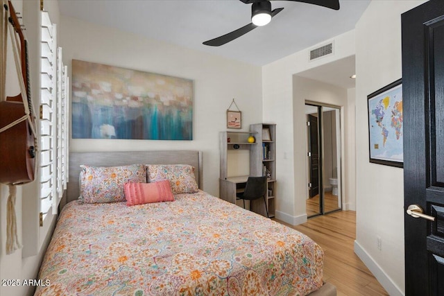 bedroom with visible vents, a ceiling fan, baseboards, and wood finished floors