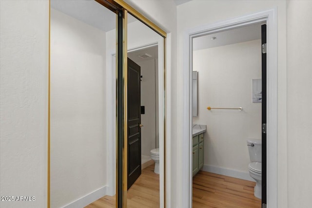 bathroom with vanity, toilet, wood finished floors, and baseboards