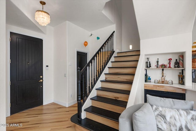 foyer featuring stairway, baseboards, a bar, and wood finished floors