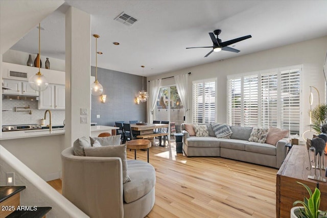 living room with light wood-style flooring, a ceiling fan, and visible vents