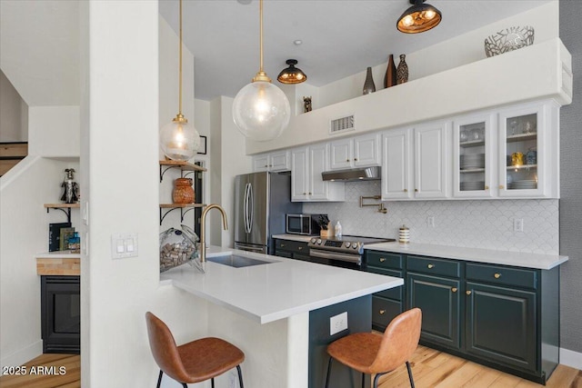 kitchen featuring a sink, a peninsula, appliances with stainless steel finishes, a breakfast bar area, and decorative backsplash