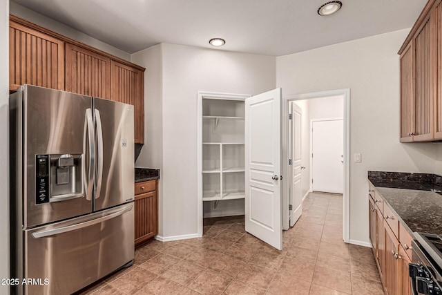 6826 W St Charles Ave, Laveen, AZ 85339 - kitchen with stainless steel fridge, dark stone countertops, stove, light tile patterned flooring, and brown cabinets