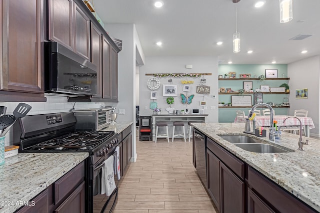 kitchen featuring light stone counters, sink, hanging light fixtures, appliances with stainless steel finishes, and light hardwood / wood-style floors