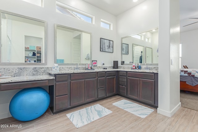 bathroom featuring a high ceiling, hardwood / wood-style floors, ceiling fan, and vanity