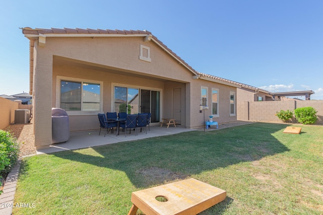 back of house featuring cooling unit, a lawn, and a patio