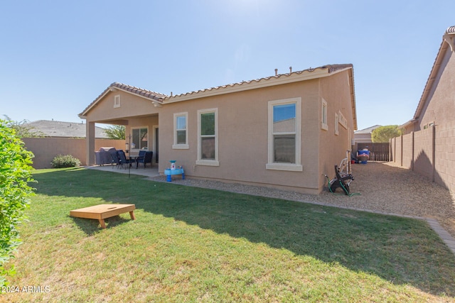 back of property with a lawn and a patio