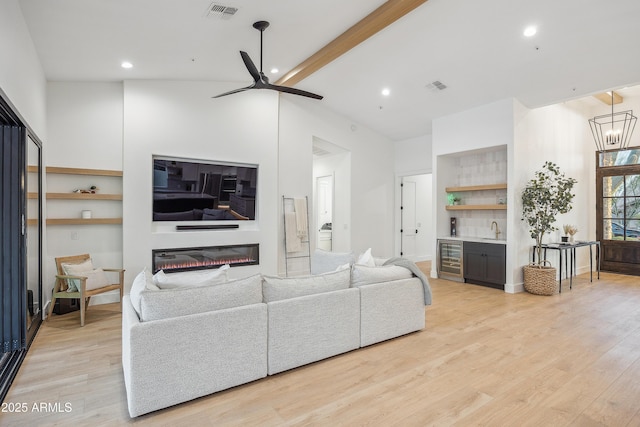 living room featuring wet bar, beverage cooler, ceiling fan, and light hardwood / wood-style flooring