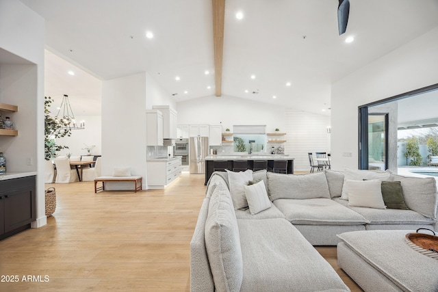 living room featuring sink, beam ceiling, high vaulted ceiling, light hardwood / wood-style floors, and a chandelier