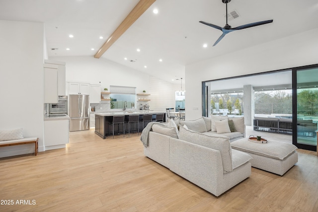 living room with high vaulted ceiling, sink, ceiling fan, light hardwood / wood-style floors, and beam ceiling