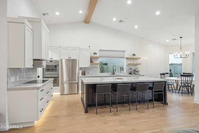 kitchen with stainless steel appliances, a center island, light hardwood / wood-style floors, white cabinets, and decorative light fixtures