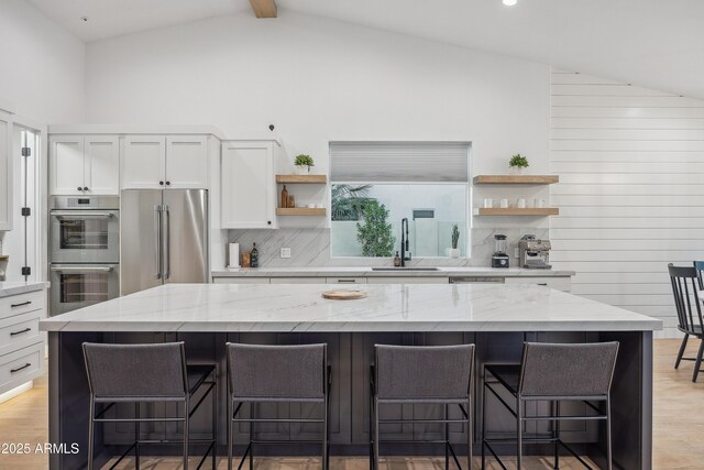 kitchen featuring a kitchen bar, a center island, white cabinets, and appliances with stainless steel finishes