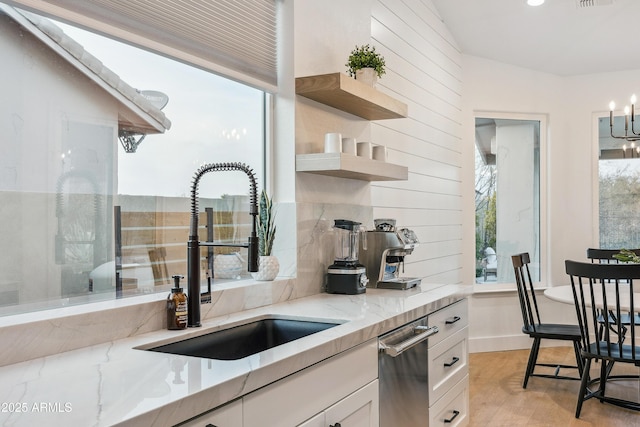 kitchen with white cabinetry, sink, light stone countertops, and light hardwood / wood-style floors