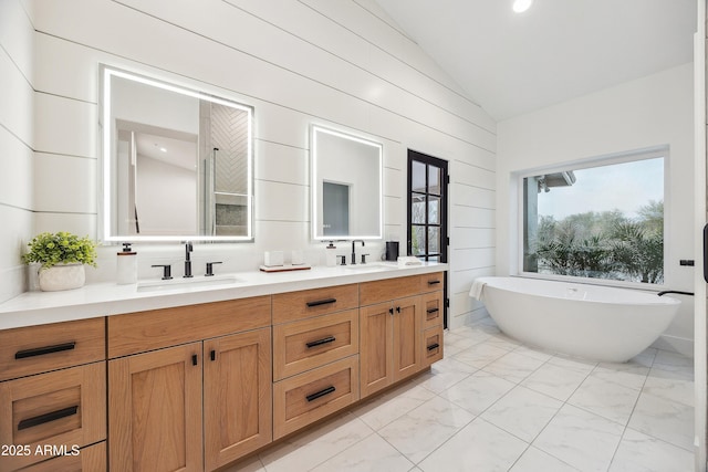 bathroom featuring vanity, a bath, and vaulted ceiling