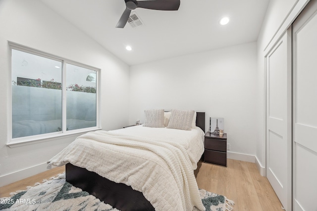 bedroom featuring a closet, lofted ceiling, ceiling fan, and light hardwood / wood-style flooring