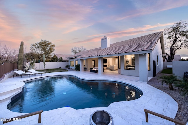 pool at dusk with pool water feature and a patio area