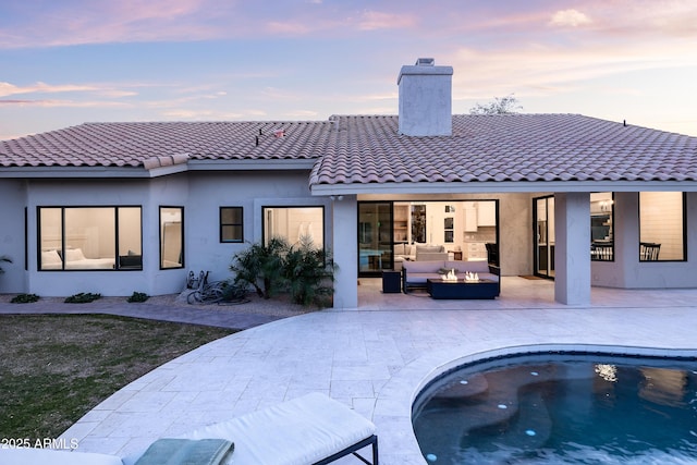 back house at dusk featuring an outdoor living space and a patio