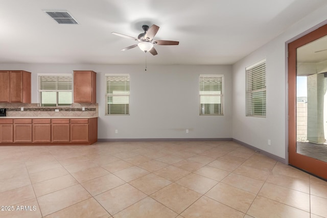 kitchen with light countertops, tasteful backsplash, visible vents, a ceiling fan, and brown cabinets