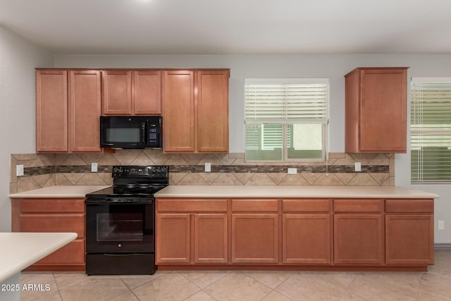 kitchen with brown cabinetry, black appliances, light countertops, and tasteful backsplash