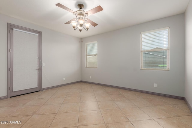 empty room featuring light tile patterned floors, a wealth of natural light, baseboards, and a ceiling fan