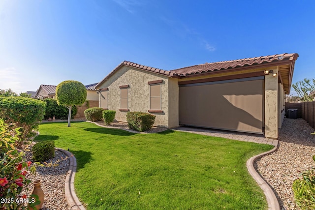 exterior space featuring a tiled roof, stucco siding, fence, and a lawn