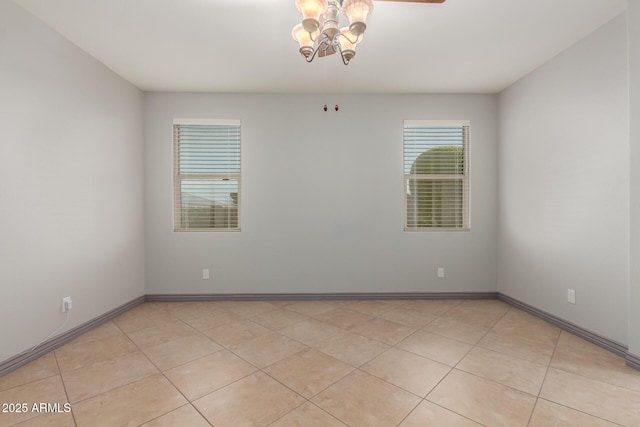 spare room with baseboards, light tile patterned floors, and a ceiling fan